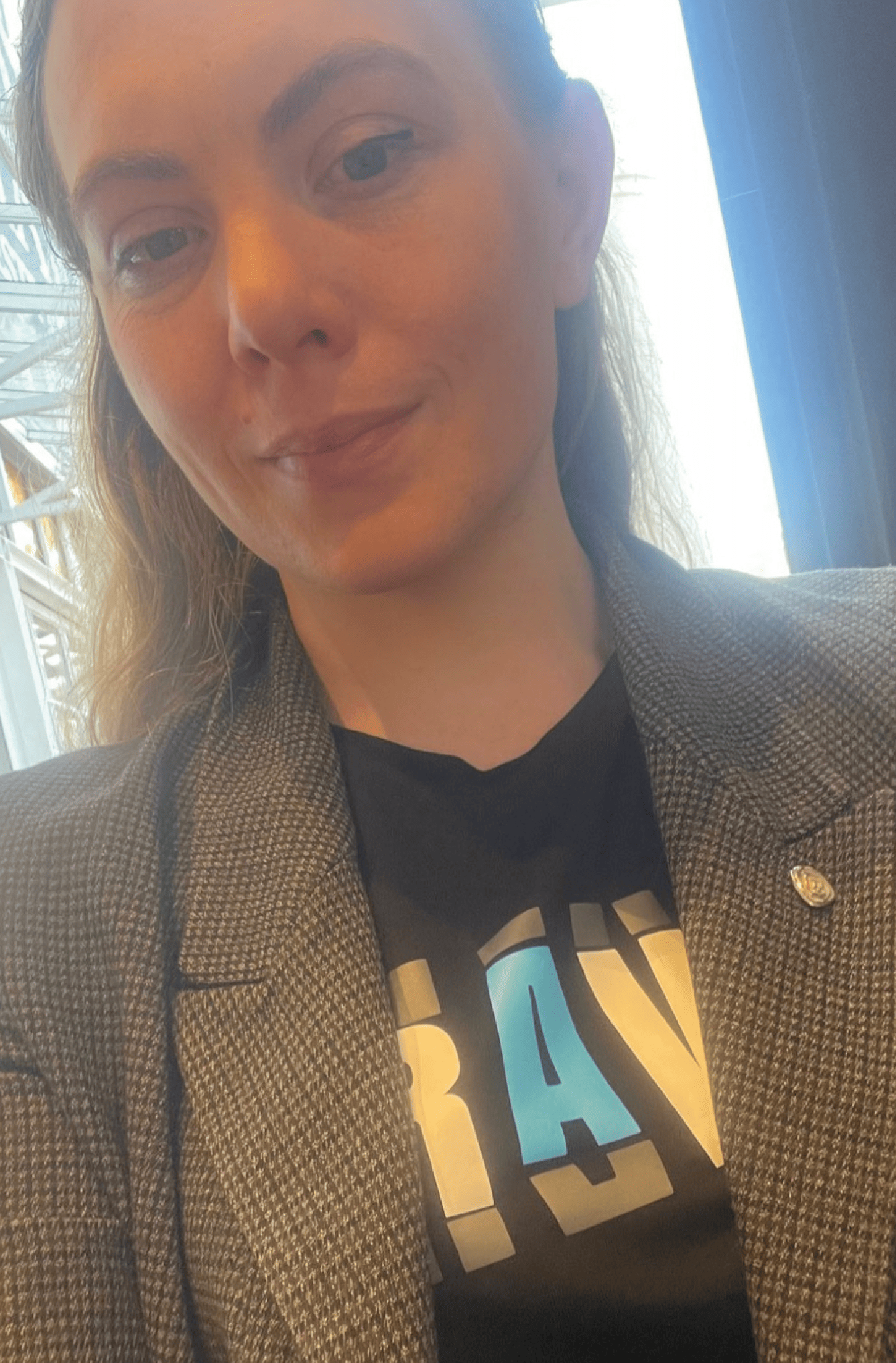 Woman wearing black t-shirt styled with a tailored jacket and silver pin