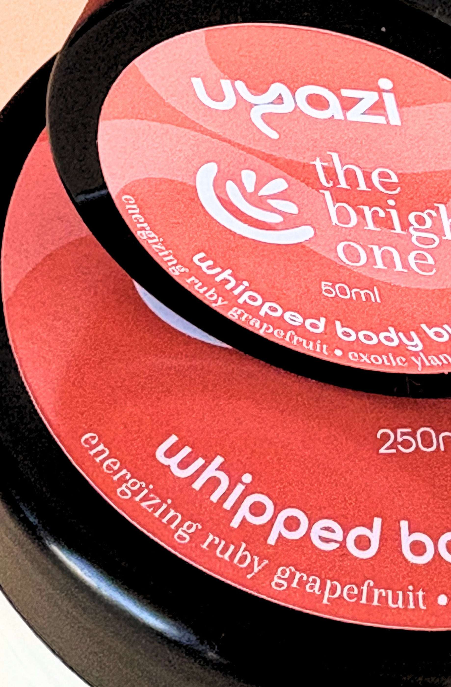 Close-up of Uyazi whipped body butter containers with visible branding and product name.