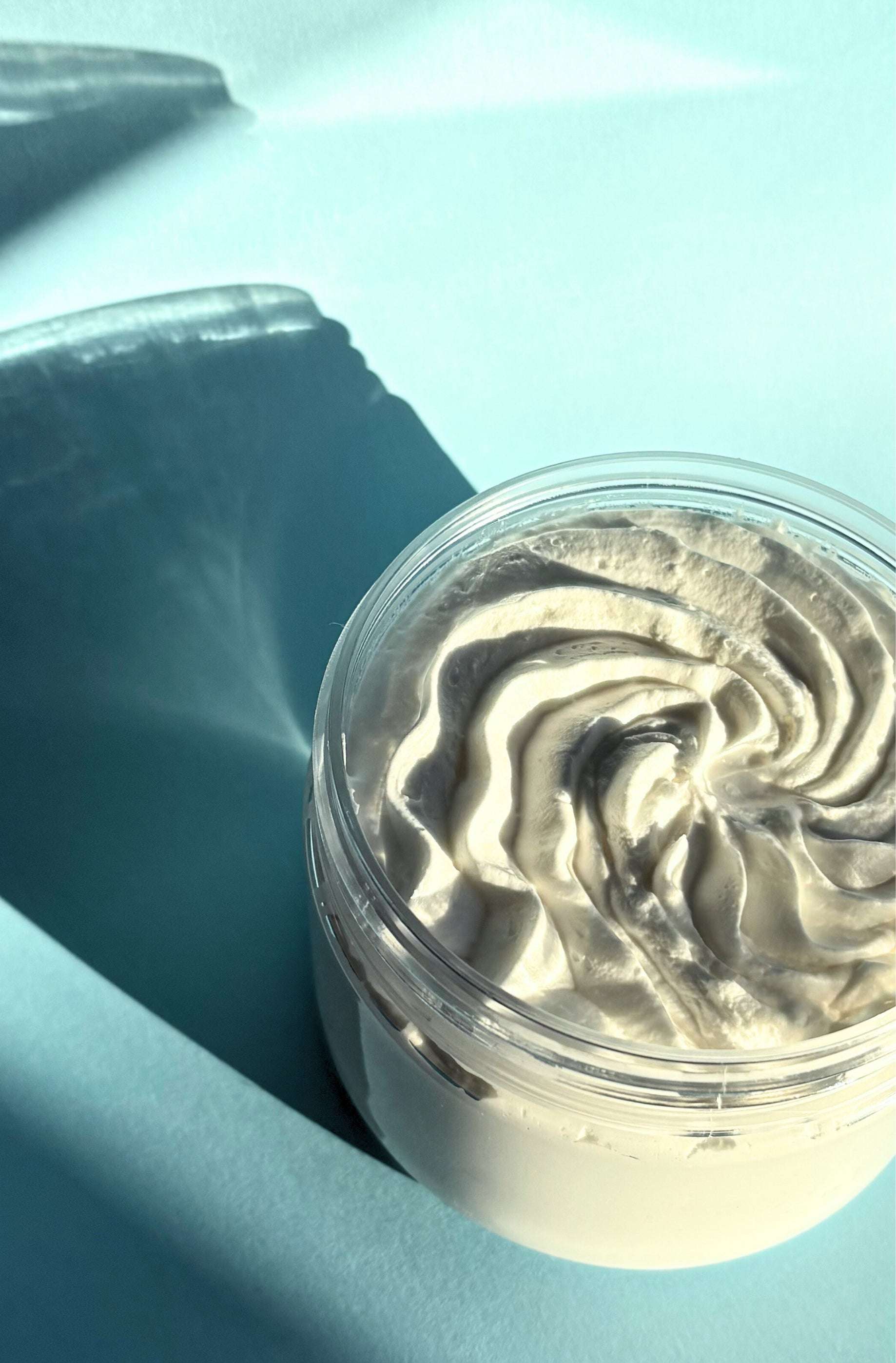 Jar of whipped body butter on a light blue background
