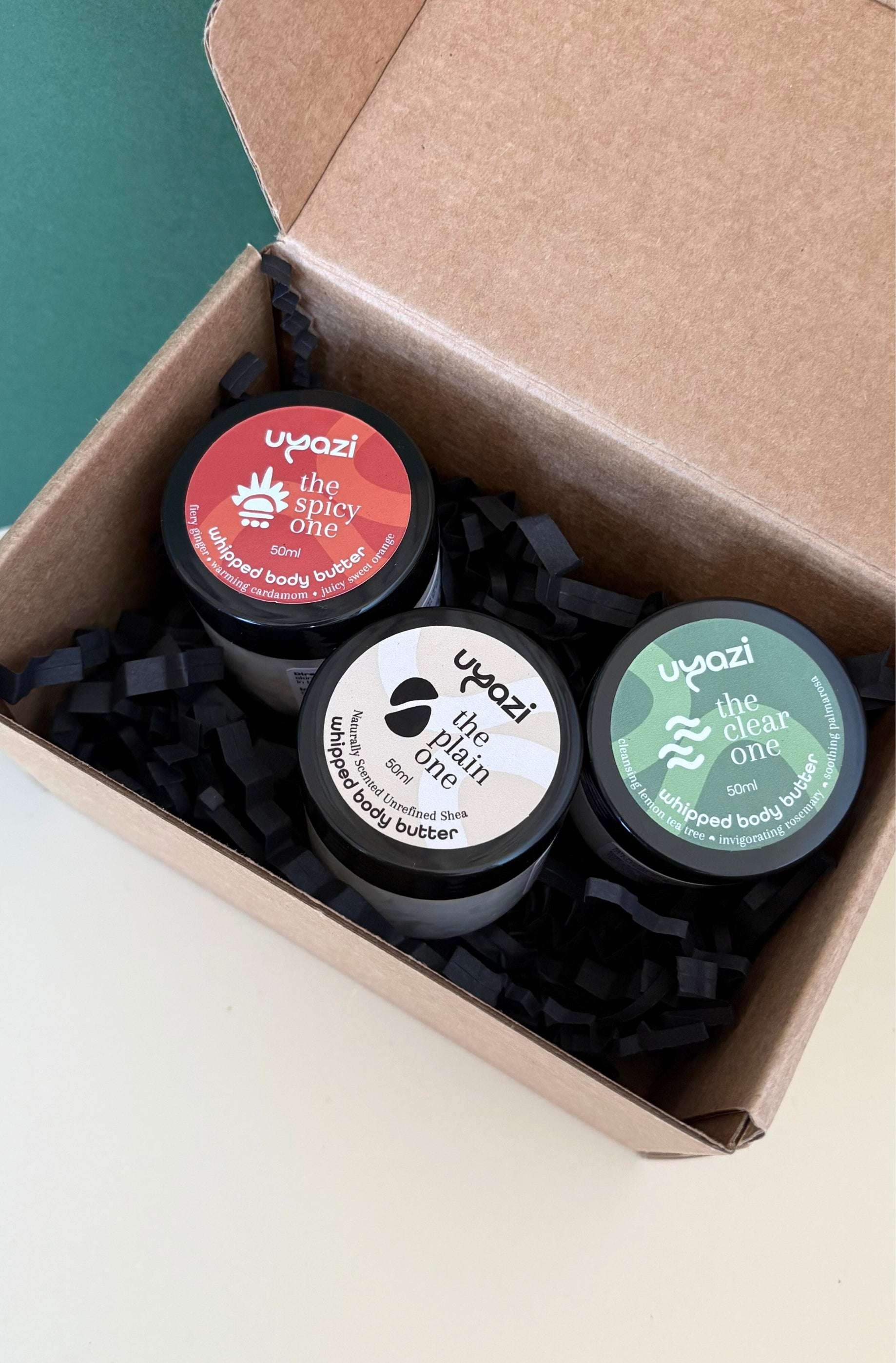 Three containers of Uyazi whipped body butter in a cardboard box.