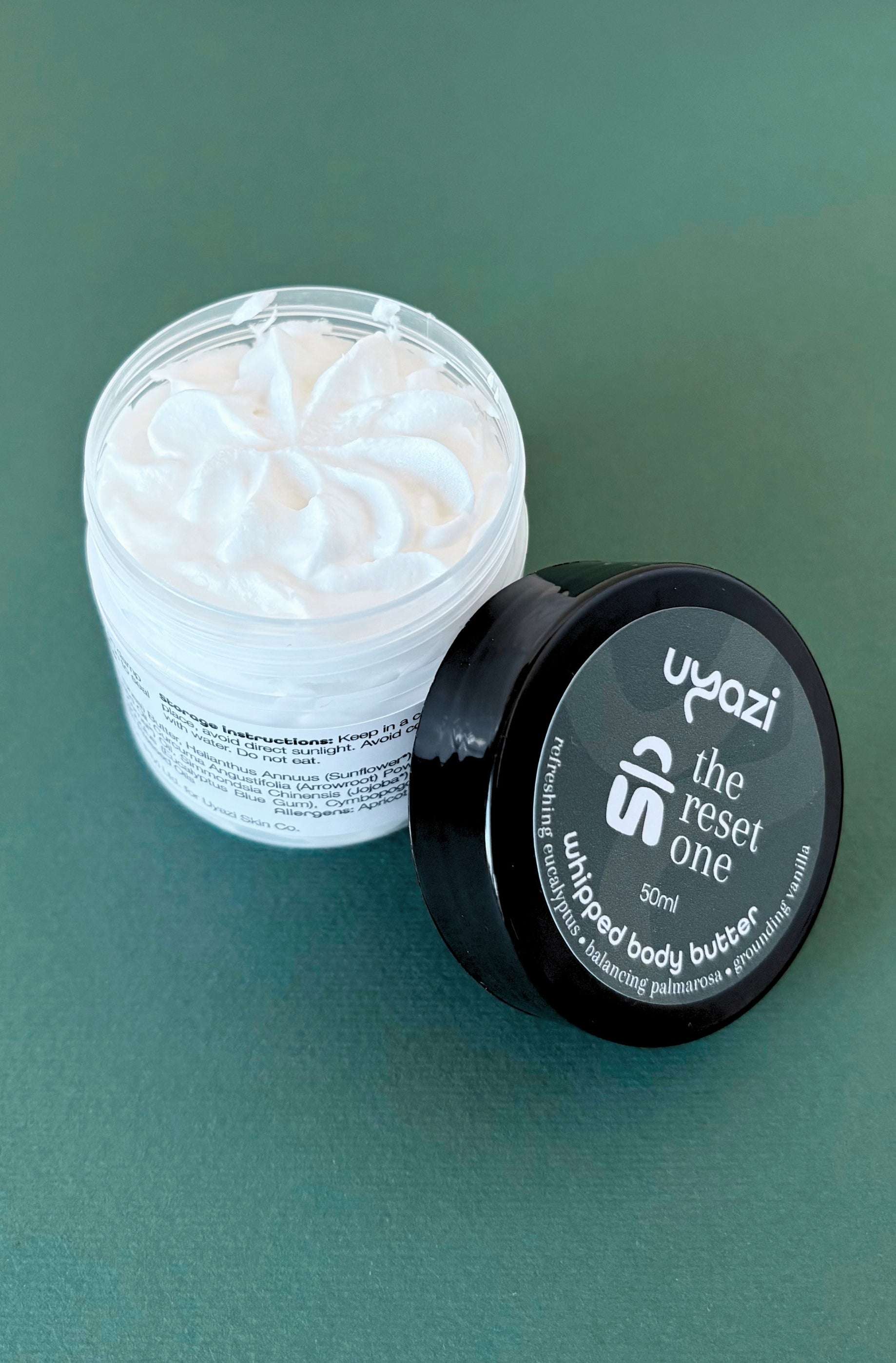 Uyazi whipped body butter container with black lid on a green background