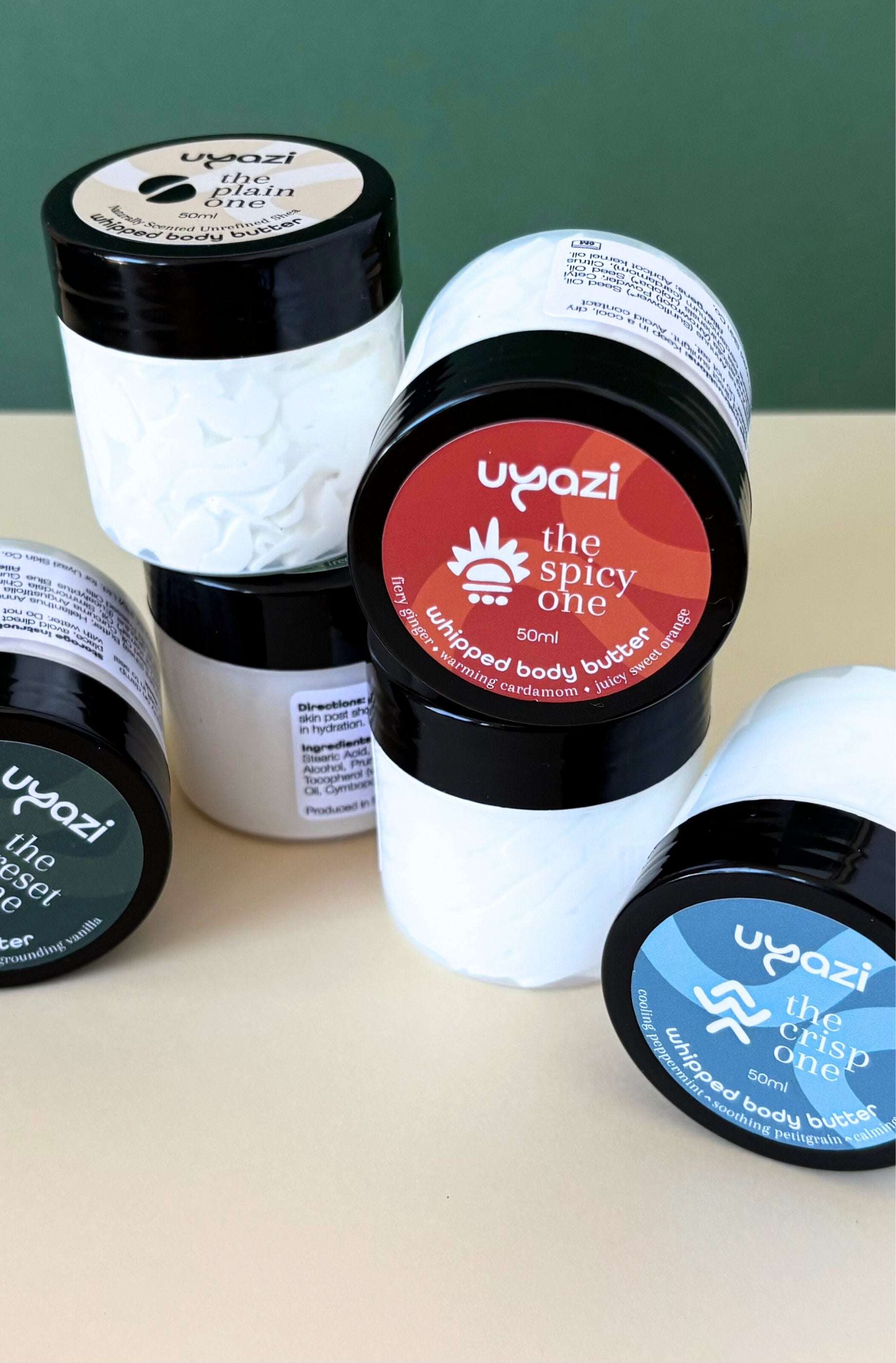Assorted 50ml jars of uyazi whipped body butter on a light surface with a green background
