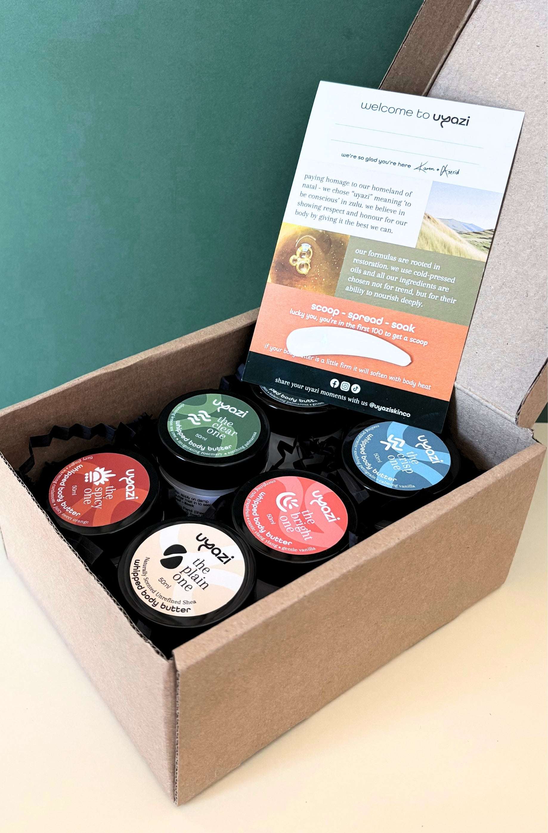 Set of six small whipped body butters with lids in a cardboard box, featuring a branded card on top.