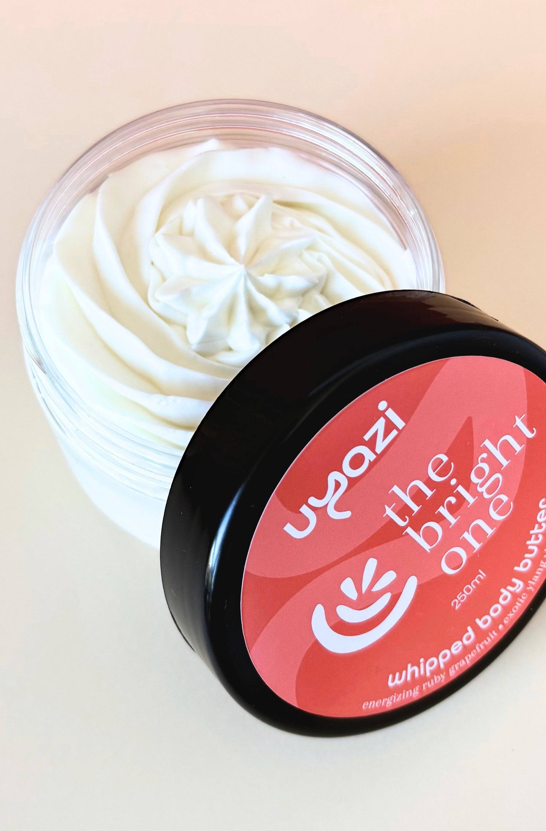 Jar of whipped body butter with a orange and peachy label on a beige background