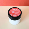 Jar of 'the bright one' whipped body butter with a pink label on a beige surface.
