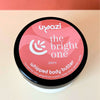 Uyazi The Bright One whipped body butter container on an orange and peachy background