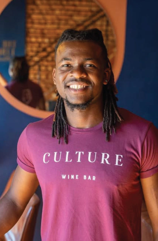 Man wearing a custom branded 'Culture Wine Bar' t-shirt in front of a blue wall in Cape Town's top rated wine bar