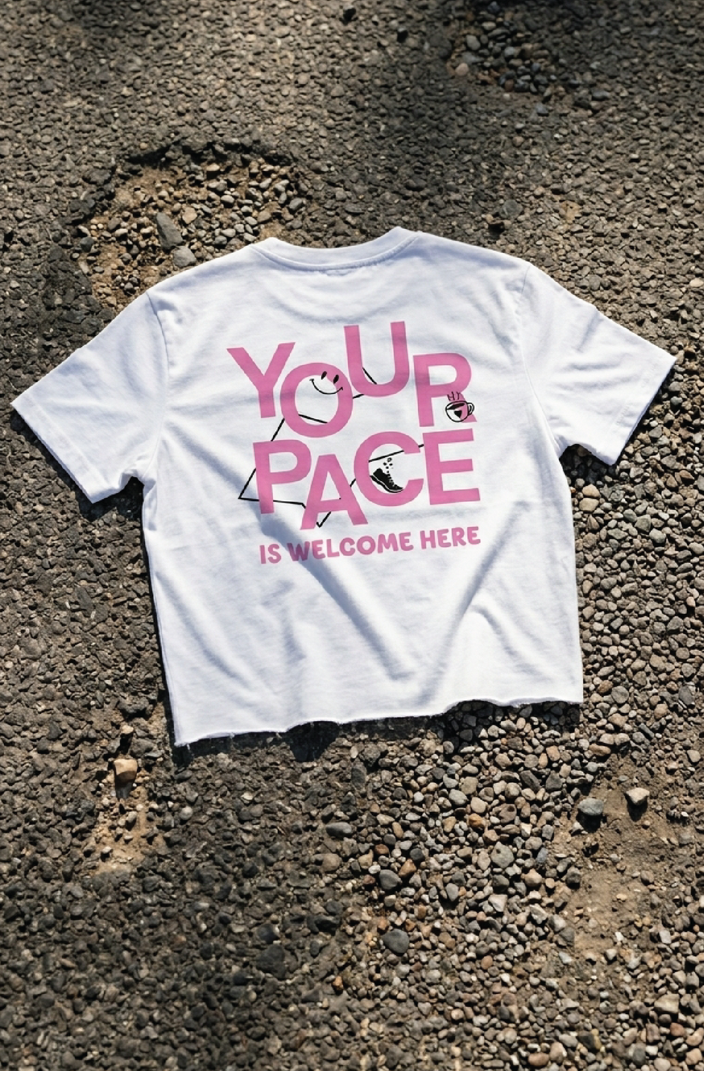 White t-shirt with pink text "your pace" a runners crop top on a textured surface