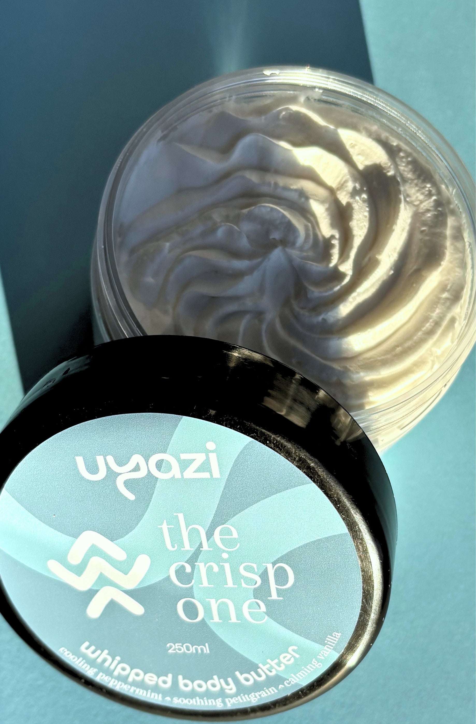 Uyazi whipped body butter container with visible whipped body butter on a blue background