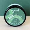 Uyazi whipped body butter container with green label on a beige surface and green background