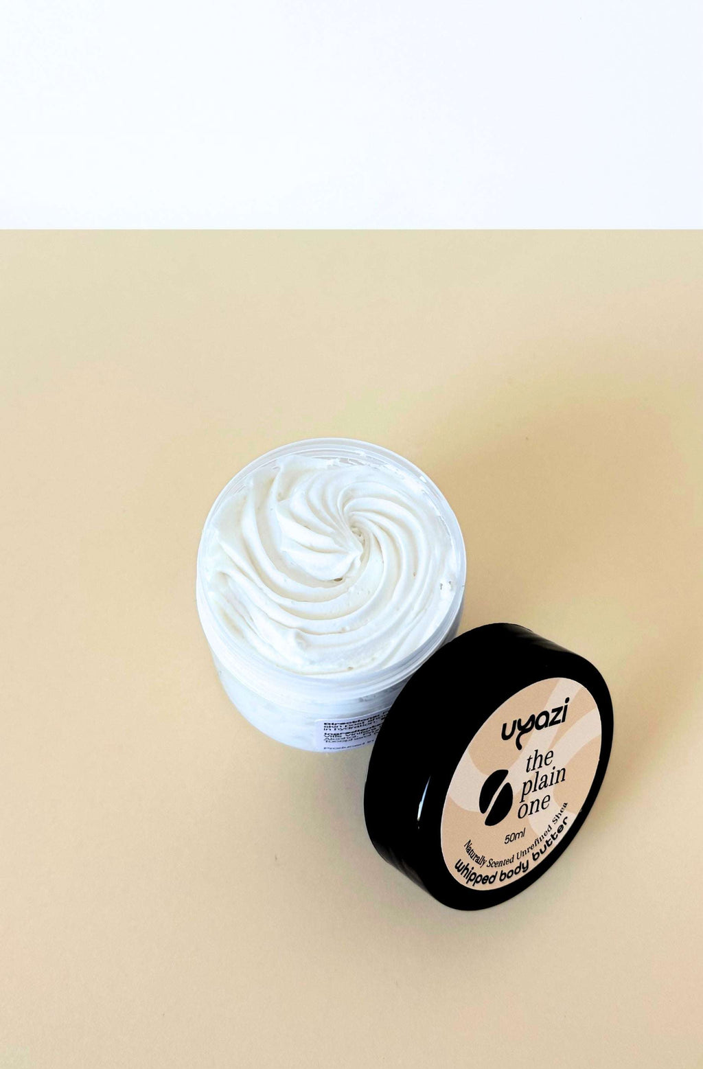 Jar of whipped body butter with a visible brand label on a beige background