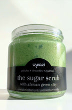 Jar of green sugar scrub with a black label on a white background