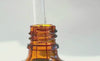 video showing various angles of body oil coming out of glass pipette and dripping on the glass bottle and label